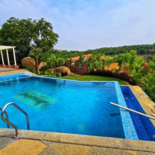 a large swimming pool with blue water in a yard at Unwind Farm Retreat in Hyderabad