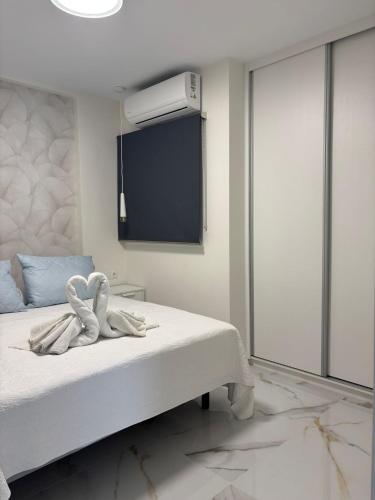 a bedroom with a white bed with a tv on the wall at Marco Apartment By Torremolinos On-line in Torremolinos