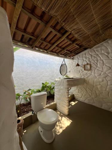 a bathroom with a toilet and a sink at Pousada Quintal Caraíva in Caraíva
