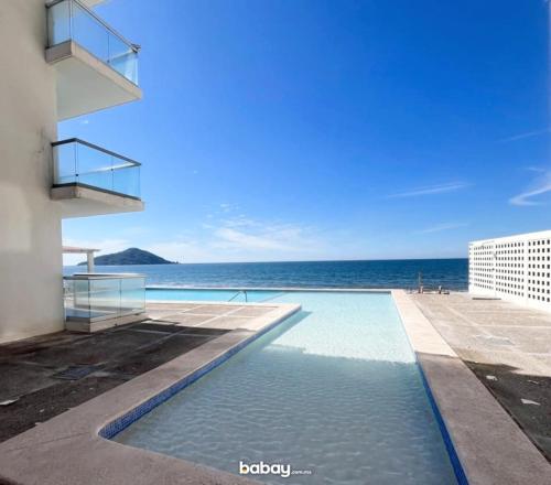 a swimming pool with the ocean in the background at Departamento con vista al mar, Marina del sol-Zona Cerritos in Mazatlán