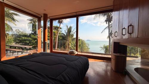 a bedroom with a bed with a view of the ocean at Villa Amrita - Oceanfront Villa with Private Beach in Ko Phangan