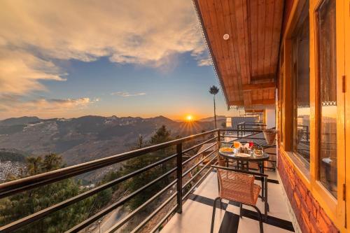 a balcony with a table and a view of the mountains at Gadegal Homestay Narkanda - Rooms & Pahadi Café in Shimla