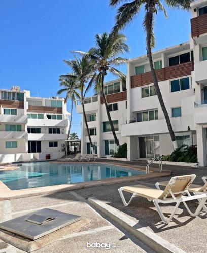 a swimming pool in front of a building with palm trees at Departamento con vista al mar, Marina del sol-Zona Cerritos in Mazatlán