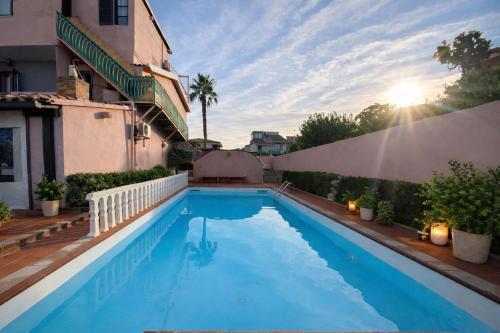 a swimming pool in front of a building with the sun setting at Vincent house in Quartu SantʼElena
