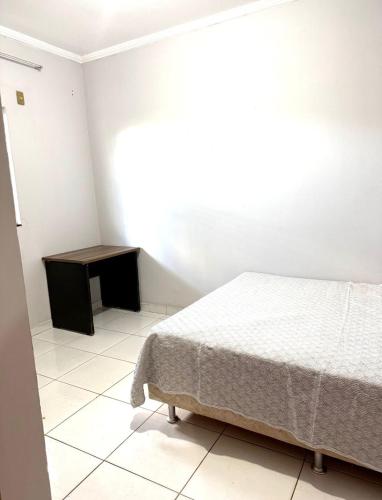 a bedroom with a bed and a small table at Cond Cristo Redentor in Trindade