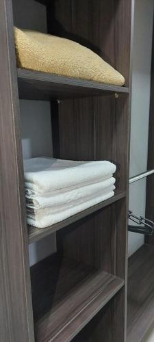 a wooden shelf with folded towels in a closet at Vila Dumont no Centro de Foz in Foz do Iguaçu