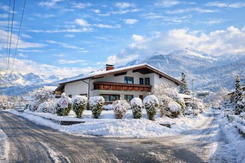a house on a snowy road with mountains in the background at Ferienwohnung Felder in Bürs