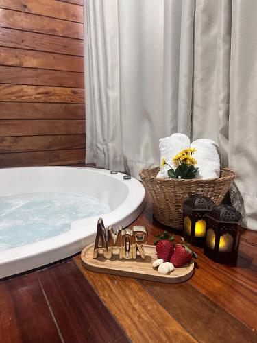a bathroom with a tub and a basket of strawberries and candles at Chalé Girassol in Venda Nova do Imigrante