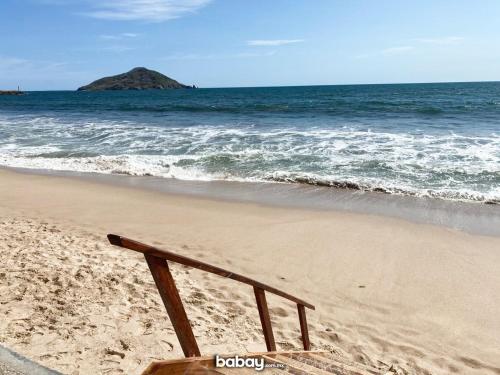 a wooden bench sitting on a beach near the ocean at Departamento con vista al mar, Marina del sol-Zona Cerritos in Mazatlán