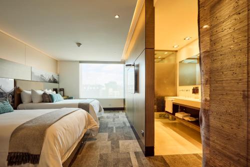 a hotel room with two beds and a bathroom at EK Hotel By Preferred Hotels Group in Bogotá