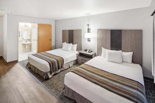 a hotel room with two beds and a bathroom at Aviator Suites Hotel Juneau Airport by Aspen Hotels in Juneau