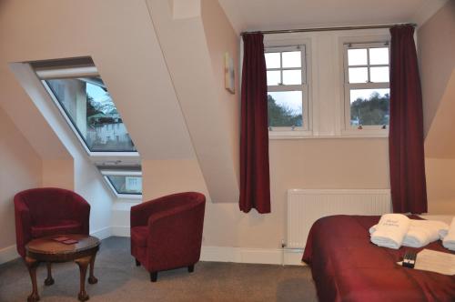 a bedroom with a bed and a chair and a window at Hotel Peppers in Torquay