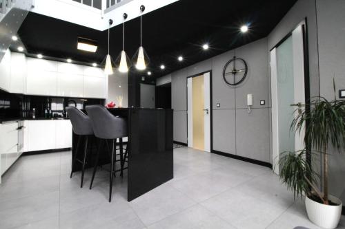 a kitchen with a black counter and stools at Bulwar Apartament in Głogów