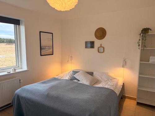 a bedroom with a bed with two lamps and a window at Guesthouse Hune in Blokhus