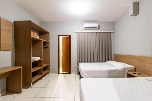 a hotel room with two beds and a closet at Vila Dumont no Centro de Foz in Foz do Iguaçu