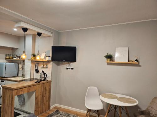 a living room with a table and a tv on the wall at Studio apartment in Rēzekne