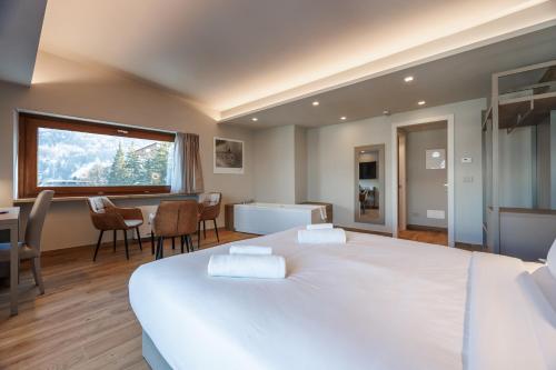 a bedroom with a large white bed and a table and chairs at Lift Hotel in Sauze dʼOulx