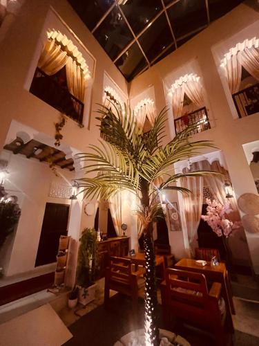 a palm tree in a room with a table and chairs at Ahmadia Heritage Hiba Guest House - Built in 1916 - Al Ras Metro Station in Dubai