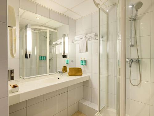ein Badezimmer mit Waschbecken und Dusche in der Unterkunft Novotel Gdansk Centrum in Danzig
