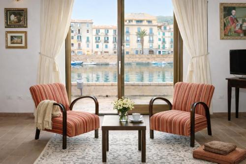 a living room with two chairs and a large window at Bosa Exclusive Apartments "Bosa Apartments" in Bosa
