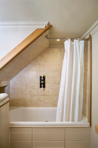 a bath tub with a shower curtain in a bathroom at Courtyard Cottages Lymington, 2 Adults only in Lymington
