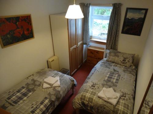 a small bedroom with two beds and a window at Smithy Cottage in Blairgowrie