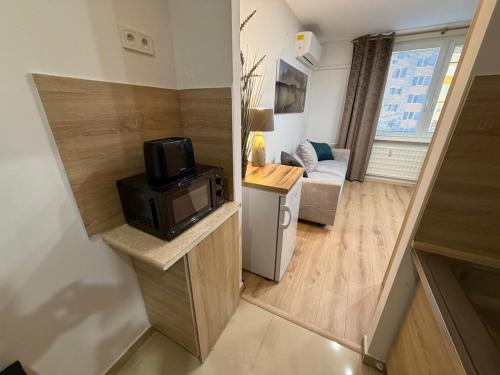 a small room with a microwave and a living room at SECRETO Apartman 1 in Komárno