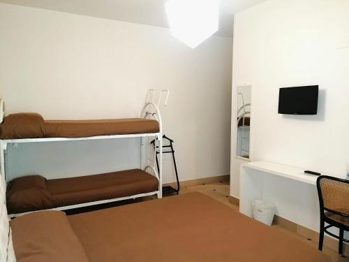 a room with two bunk beds and a desk at Hyencos Hotel Calos in Torre San Giovanni Ugento