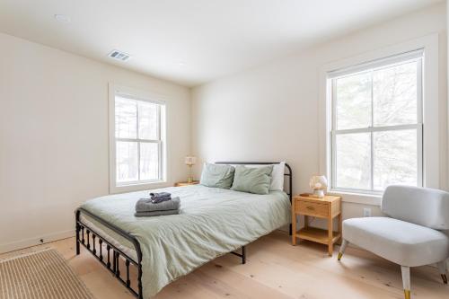 a bedroom with a bed and a chair and two windows at Lakefront with Private Dock & Canoe Kenoza Den in Jeffersonville