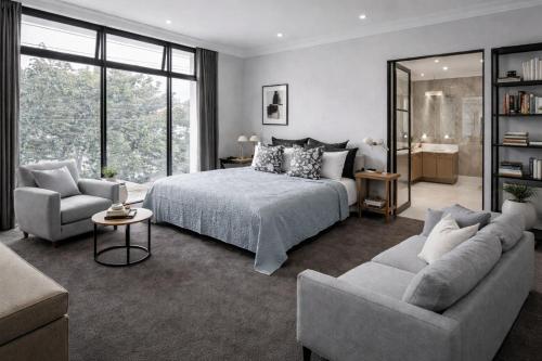 a bedroom with a bed and two chairs and a couch at Modern 2BR Apartment North Adelaide in North Adelaide