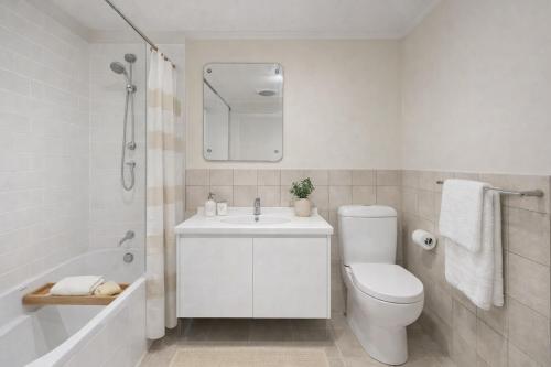 a white bathroom with a toilet and a sink at Modern 2BR Apartment North Adelaide in North Adelaide