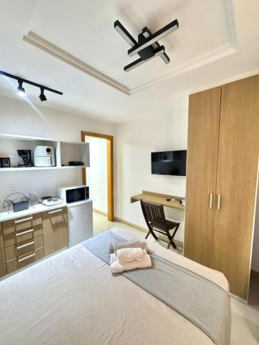 a bedroom with a bed and a desk and a kitchen at Studio c Piscina e Academia | A 13 Min de Copa in Rio de Janeiro