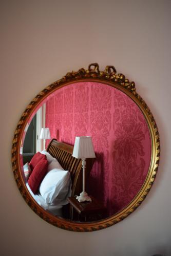 a mirror in a room with a bed and pink wallpaper at Barton Guest House in Barton upon Humber