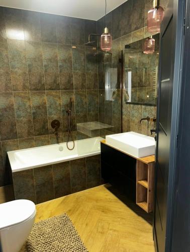 a bathroom with a tub and a sink and a toilet at S Golf Apartament in Gowinko