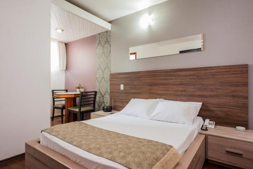 a bedroom with a bed with a wooden headboard and a table at Rainbow Motel (Adult Only) in Itupeva