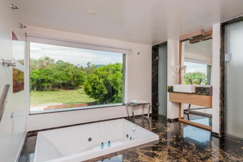 a bathroom with a large window and a tub at Rainbow Motel (Adult Only) in Itupeva