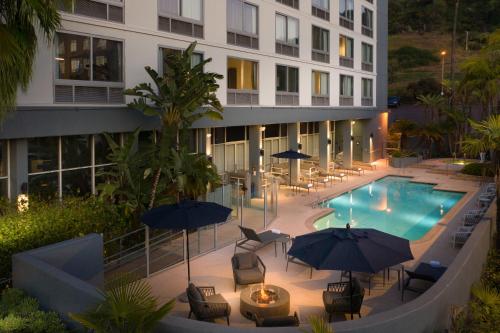 a swimming pool with chairs and umbrellas in front of a building at Courtyard by Marriott San Diego Mission Valley/Hotel Circle in San Diego