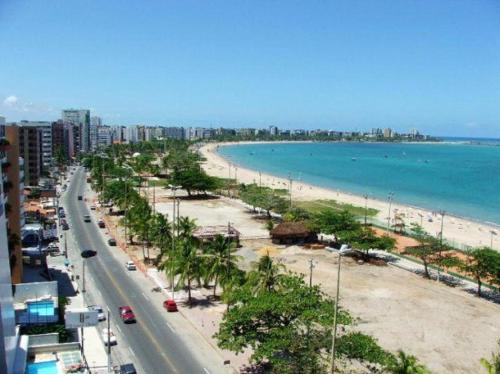 a view of a beach with palm trees and a road at Apartamento Luxo 2/4 Beira-Mar Pajuçara - Maceió in Maceió