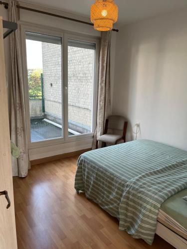 a bedroom with a bed and a large window at Appartement entier Velodrome in Roubaix