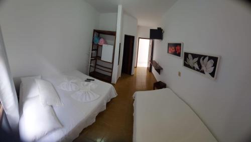a bedroom with a white bed and a television at Hotel Guarakessaba in Guaraqueçaba
