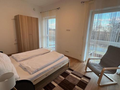 a bedroom with a bed and a chair and a window at Haus am Akazienweg in Steinberg an der Rabnitz