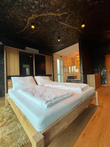 a bedroom with a large bed with white sheets at Haus am Akazienweg in Steinberg an der Rabnitz