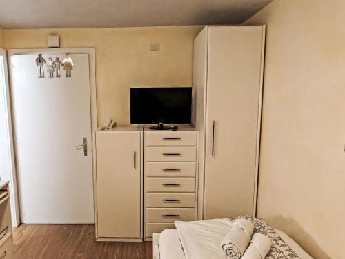 a bedroom with a tv and a white closet at Apartment Studio Turmalin by Interhome in Leukerbad