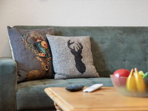 a couch with pillows with a deer pillow on it at Apartment Ker Eol by Interhome in Villars-sur-Ollon