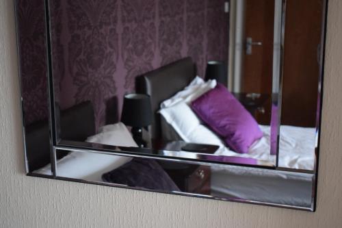 a mirror reflecting a bed with purple pillows at Barton Guest House in Barton upon Humber