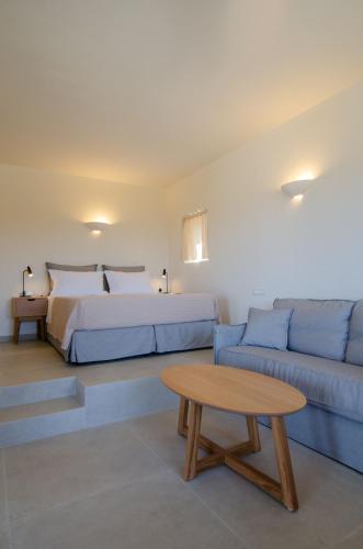 a bedroom with a bed and a couch and a table at Alma Sunset Suites in Ios Chora