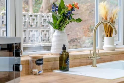 a white vase with flowers and a bottle on a kitchen counter at 4 Bed in Brecon oc-h30823 in Brecon