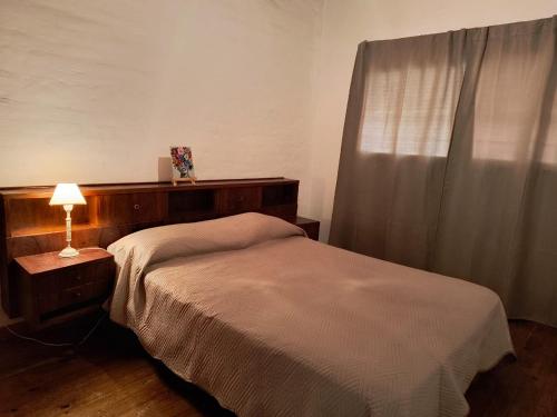 a small bedroom with a bed and a lamp at Alvear centro hospedaje 2 in General Alvear