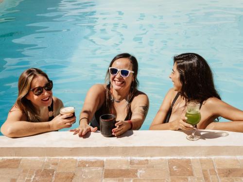 three women sitting in a swimming pool with drinks at Hotel & Suites Arges - Centro Chetumal in Chetumal