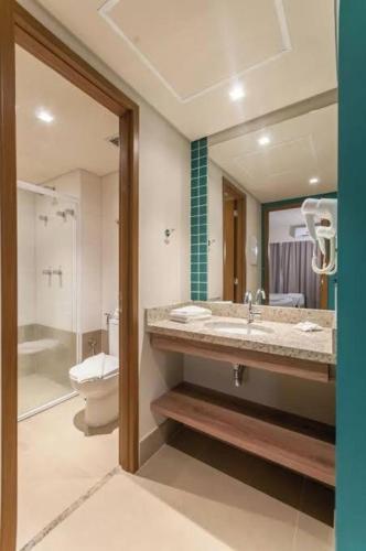 a bathroom with a sink and a toilet and a mirror at Olímpia Resort Joy in Olímpia